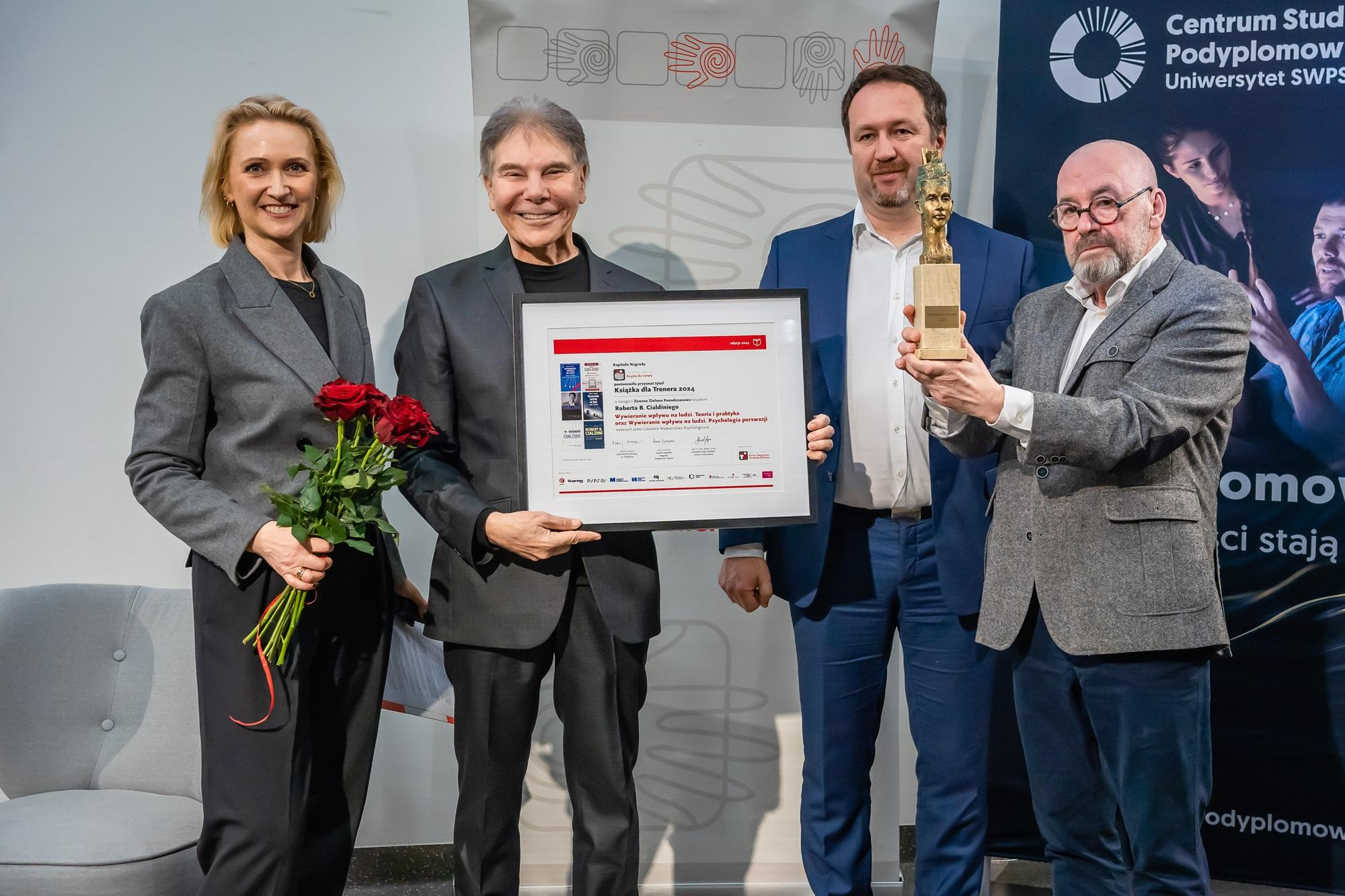 Profesor Cialdini i przedstawiciele Polskiego Towarzystwa Trenerów Biznesu z dyplomem, kwiatami i statuetką