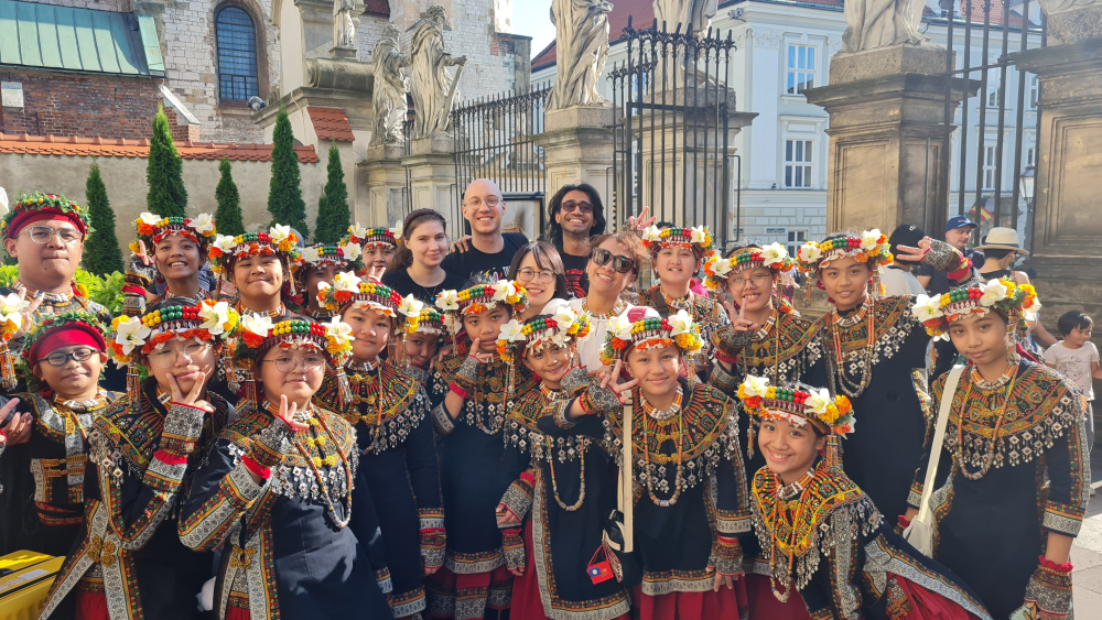 Zdjęcie grupowe. Kilkoro chórzystów USWPS z dużą grupą dzieci w tradycyjnych strojach ludu Paiwan